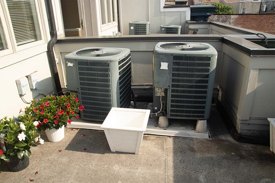 Two outdoor HVAC condenser units on a rooftop patio