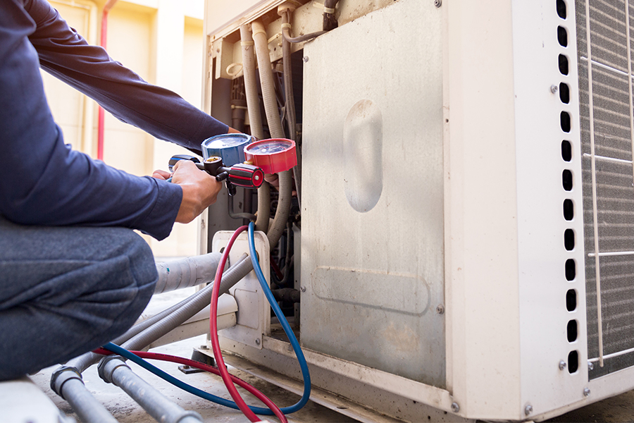 HVAC technician checking refrigerant pressure on an outdoor unit