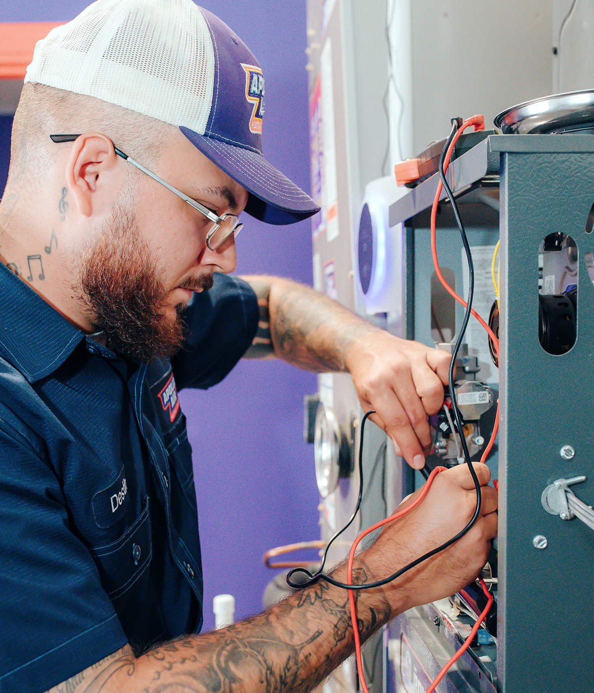 Apollo Air technician Destin focused on connecting wiring to a furnace control board during a residential heating system repair