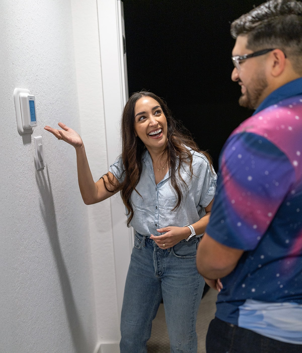 Excited homeowner reacting to a newly installed smart thermostat while an Apollo Air technician looks on