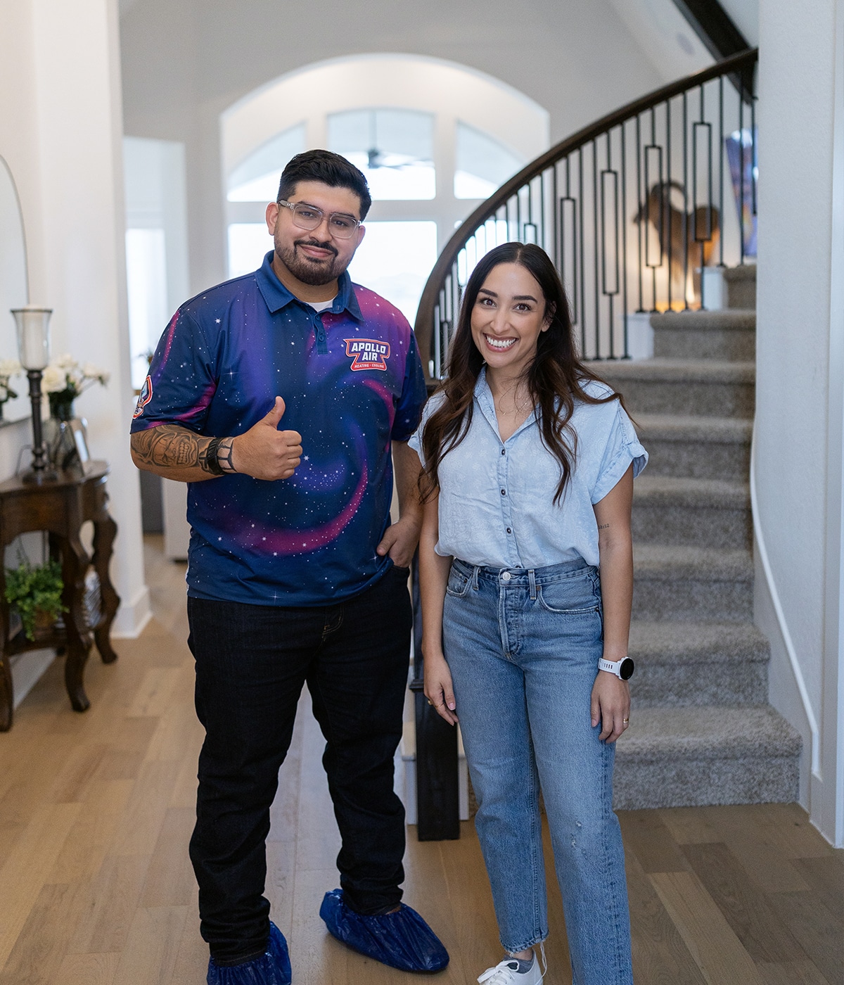 Apollo Air technician giving a thumbs up with a satisfied homeowner in a residential entryway after completing HVAC service