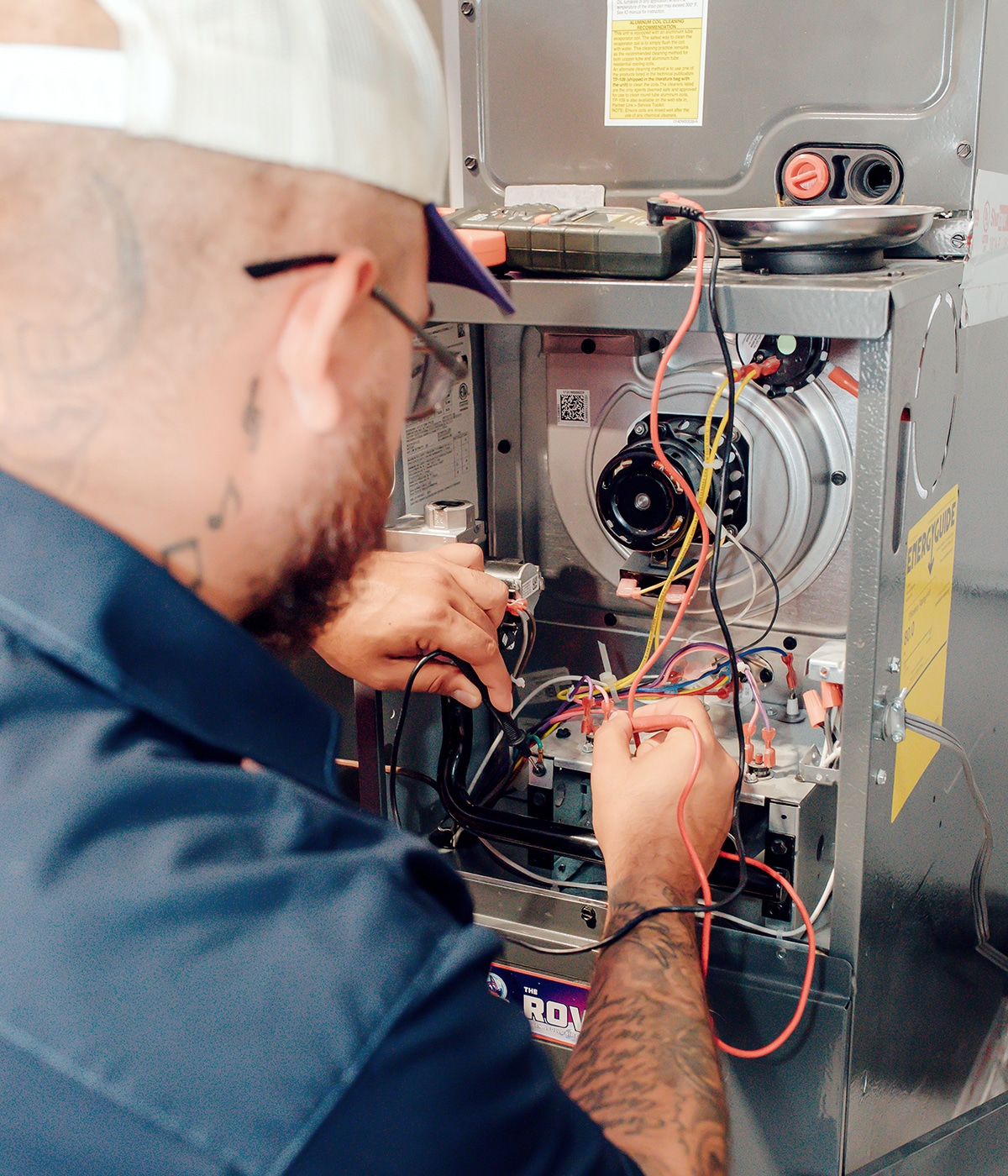 Apollo Air technician carefully routing and connecting wiring inside an open residential furnace during a heating system repair