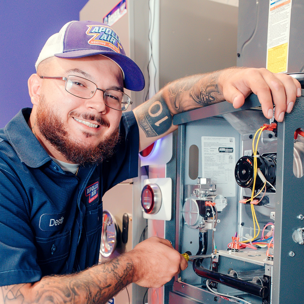 miling Apollo Air technician Destin servicing the internal components of a residential furnace heating system
