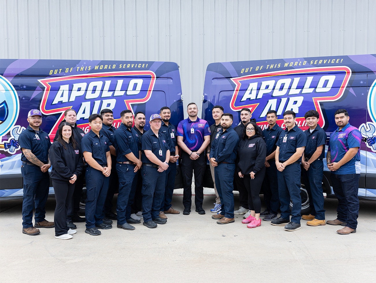 The full Apollo Air Heating and Cooling team of HVAC technicians and office staff posing in front of two branded service vans in San Antonio, Texas