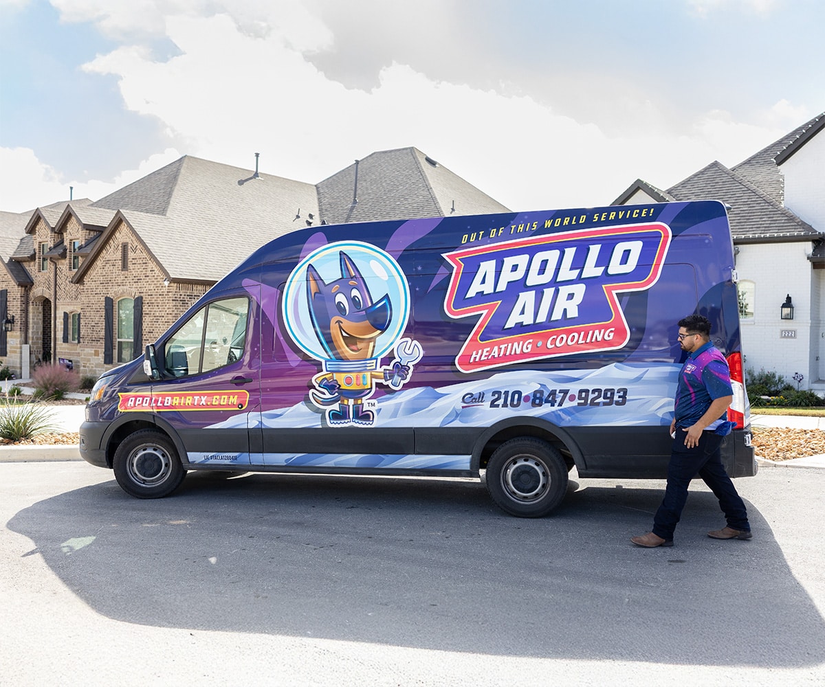 Apollo Air Heating and Cooling service technician walking beside branded company van in San Antonio, TX residential neighborhood