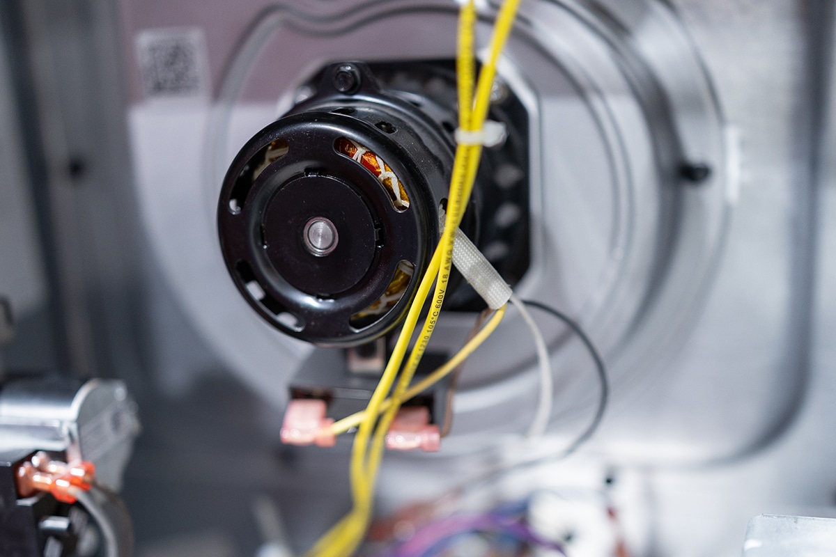 Interior view of an HVAC furnace blower motor with yellow electrical wiring and copper coils visible